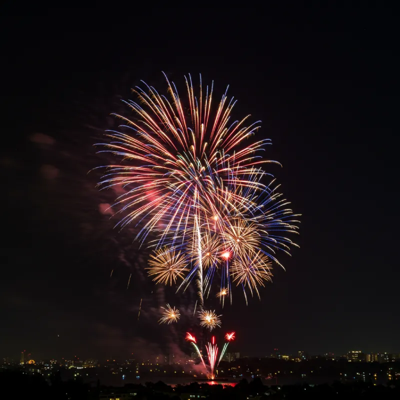 A dramatic slow-motion capture of a firework exploding with intricate light trails and vibrant red, white, blue, gold, and green colors against a dark night sky, conveying awe and power for an epic 4th of July shot.